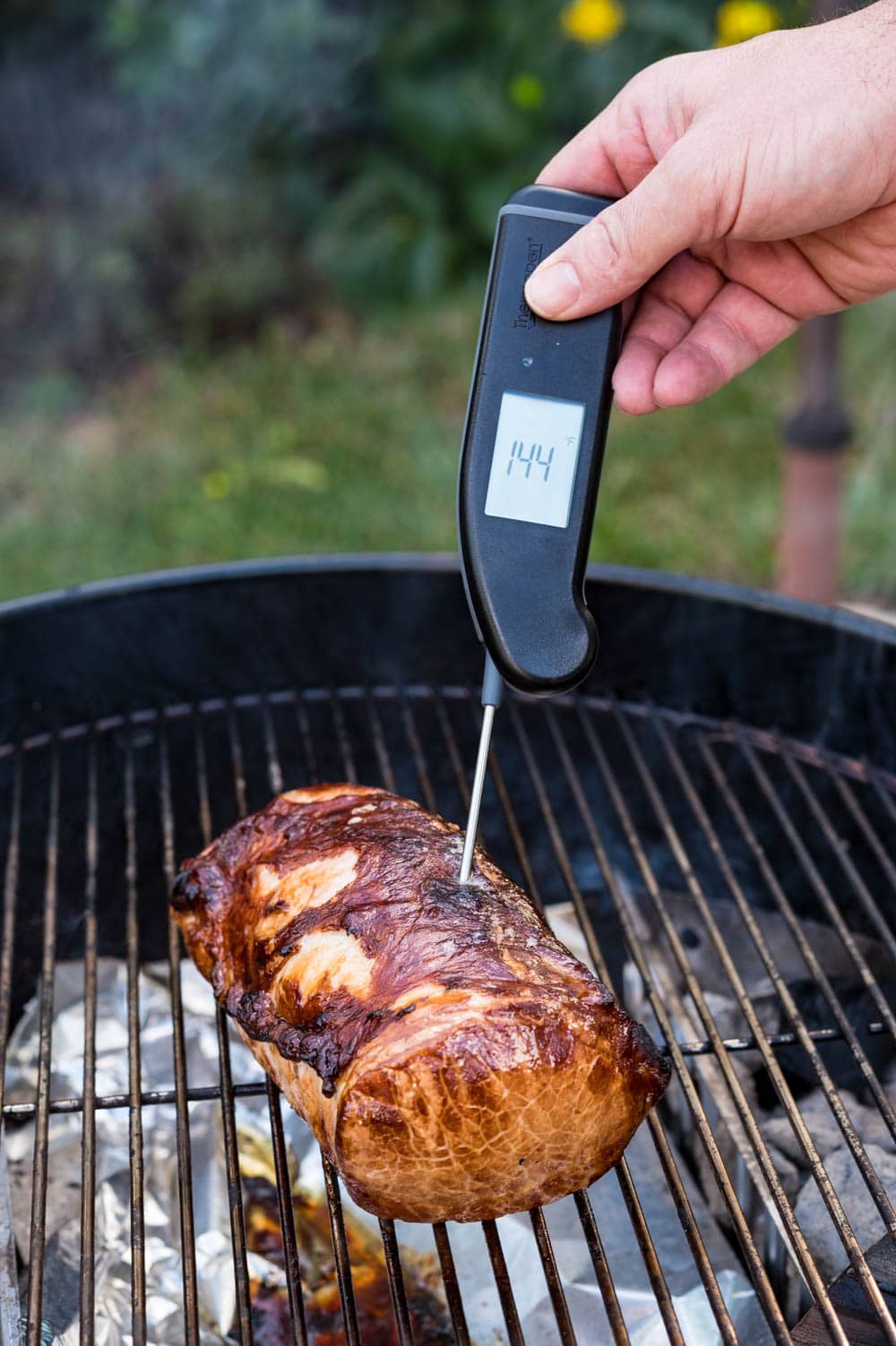 Using an instant read thermometer to check the temperature of the roast.
