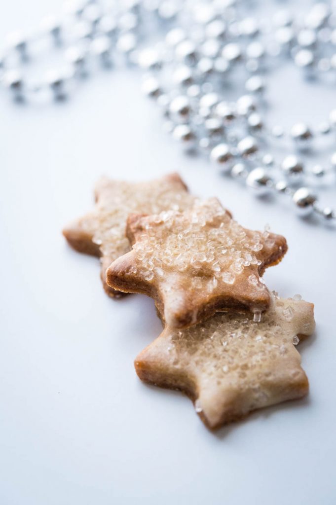 Star shaped spice cookies with sparkling sugar and vanilla glaze.