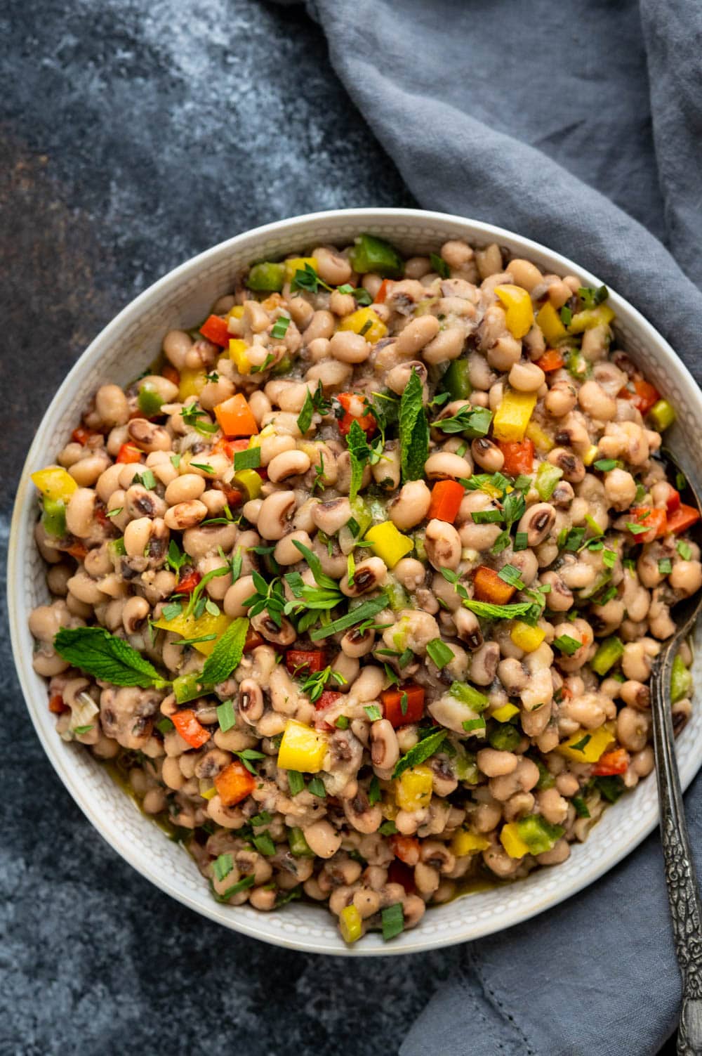 a bowl of black eyed pea salad with a spoon.
