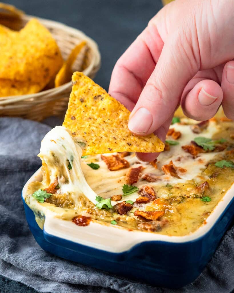 Scooping some Hatch Chile dip onto a crispy tortilla chip.