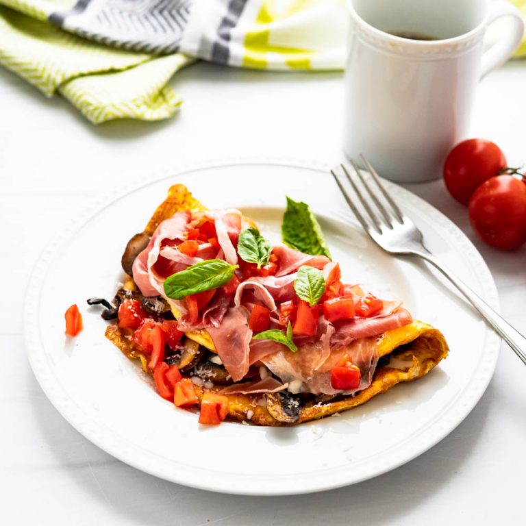 tomato mushroom omelette on a plate with fresh basil.