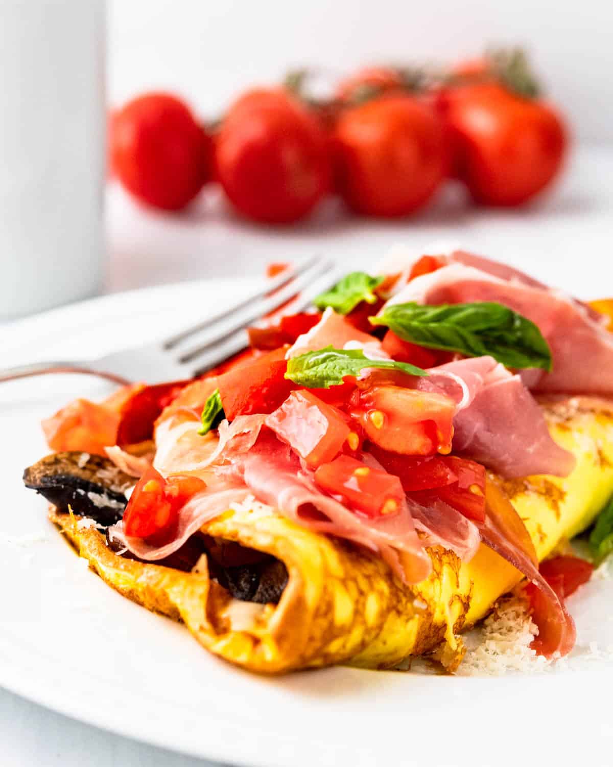 Italian Omelette on a plate with prosciutto on top.