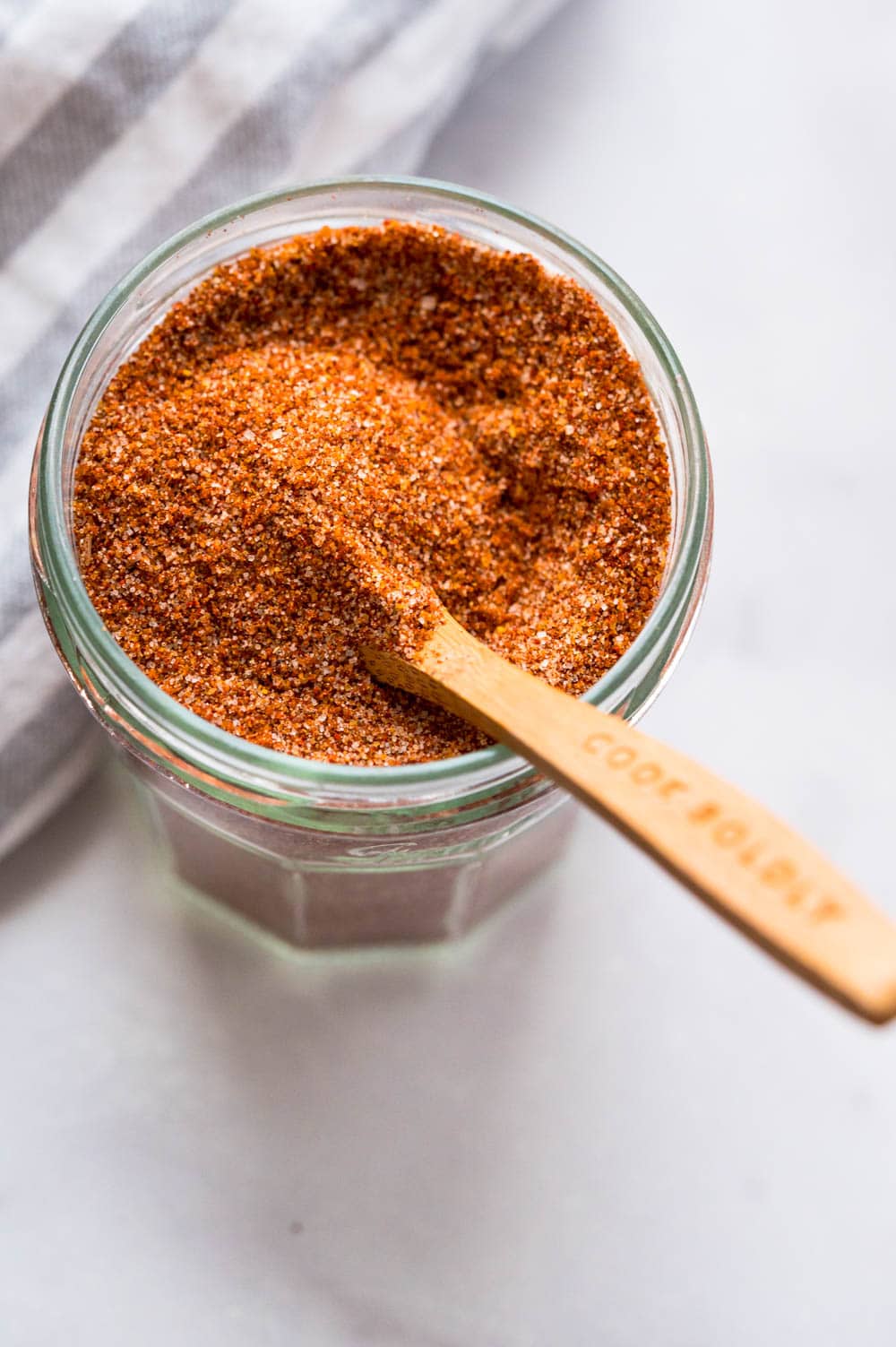 a jar of KC bbq rub with a wooden spoon.