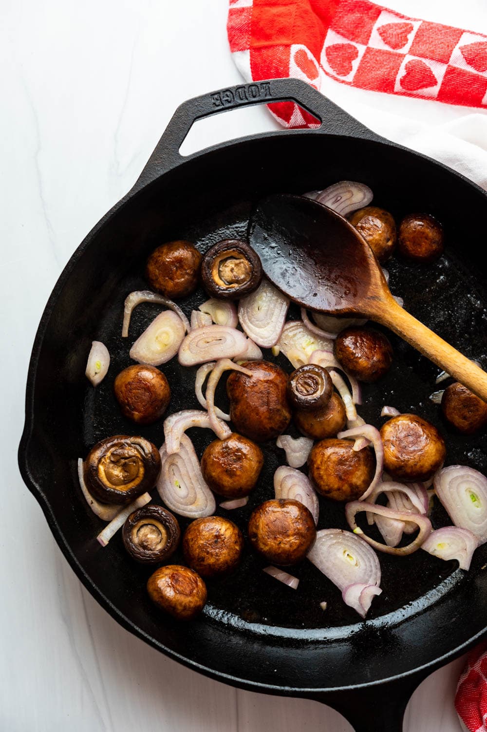 cooking mushrooms and shallots in a cast iron pan.