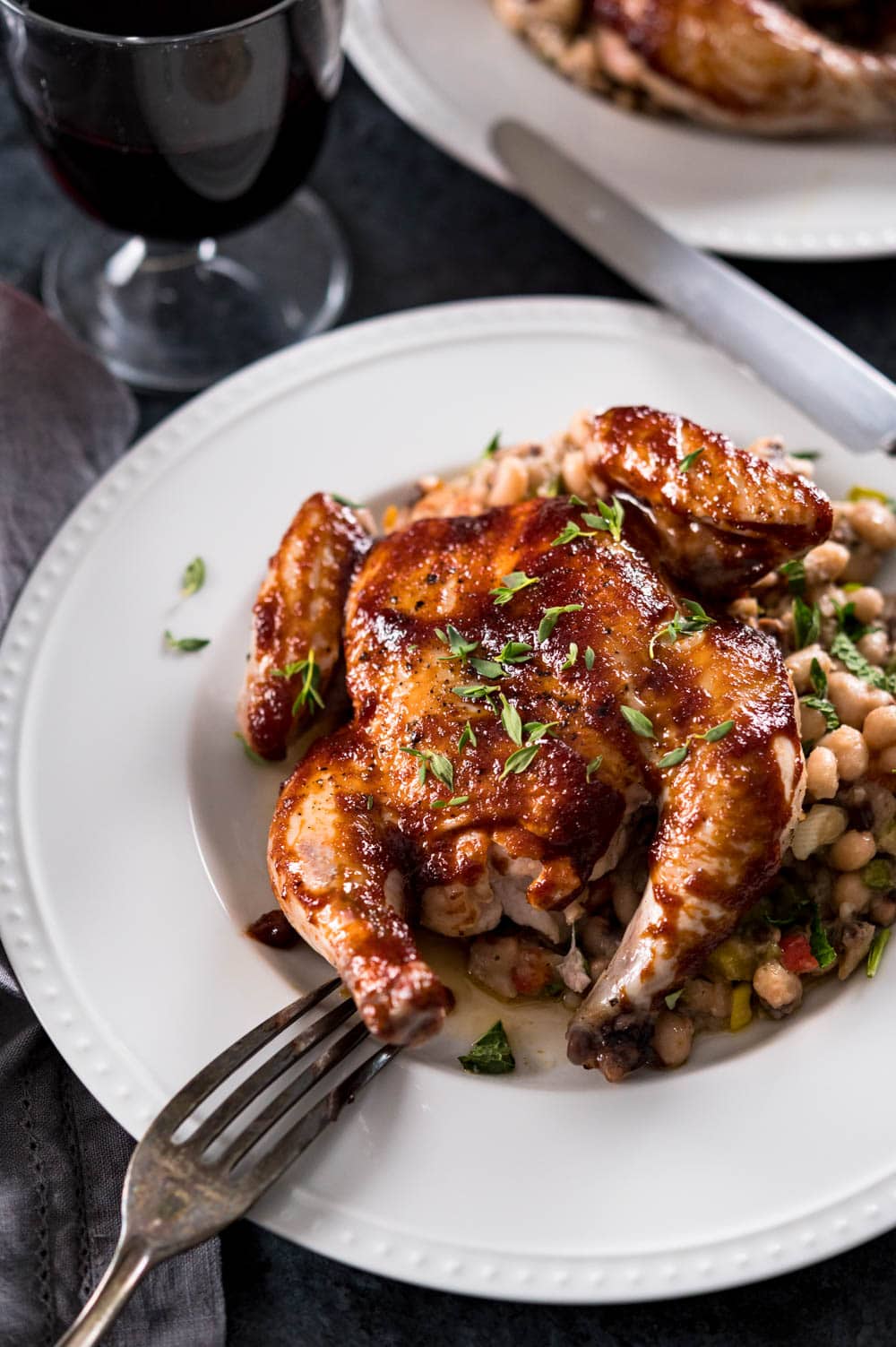 A plate with beans and a whole roasted young chicken.