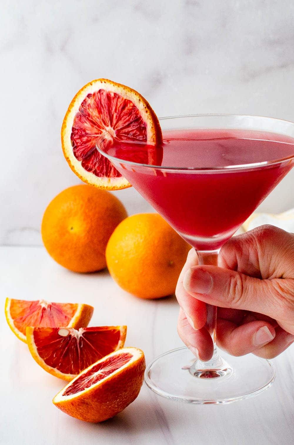Garnishing a blood orange martini with a slice of orange.