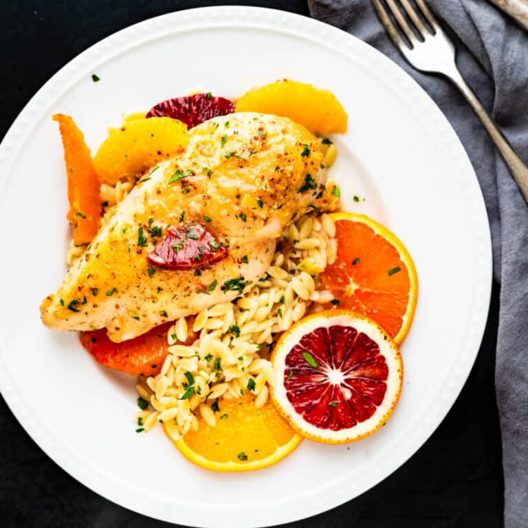 A plate of Dijon Chicken with citrus and orzo.