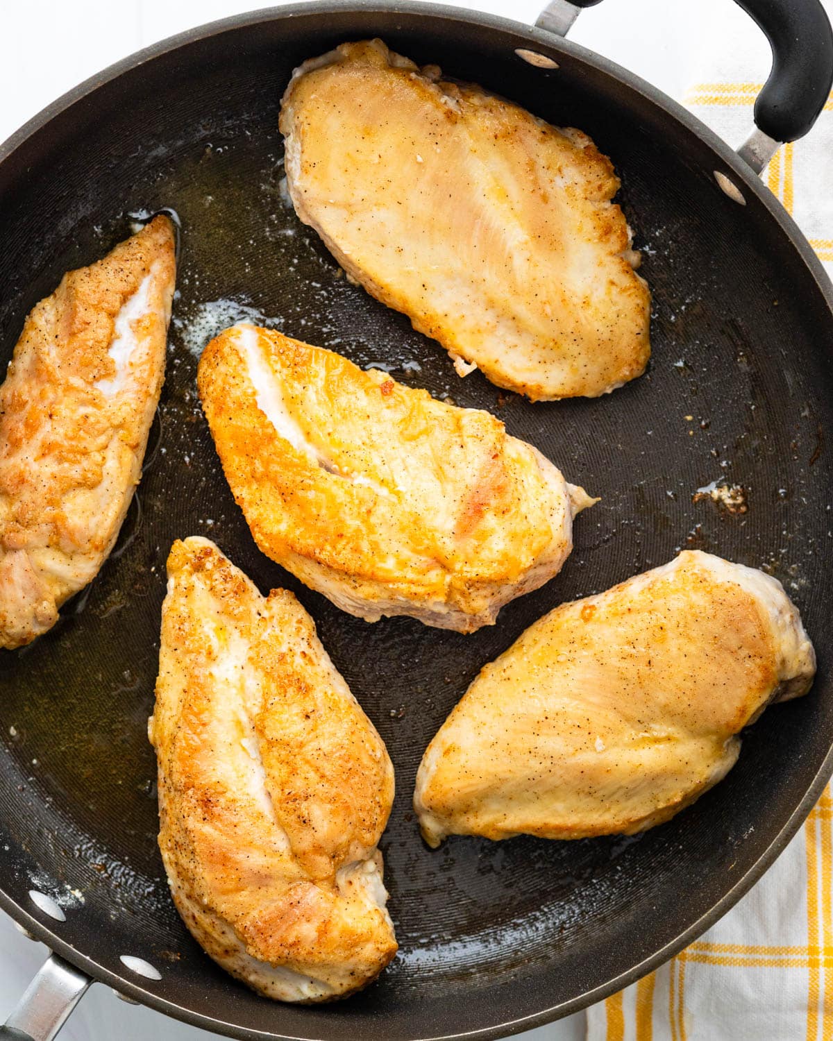 Pan frying the chicken breasts in a large skillet.