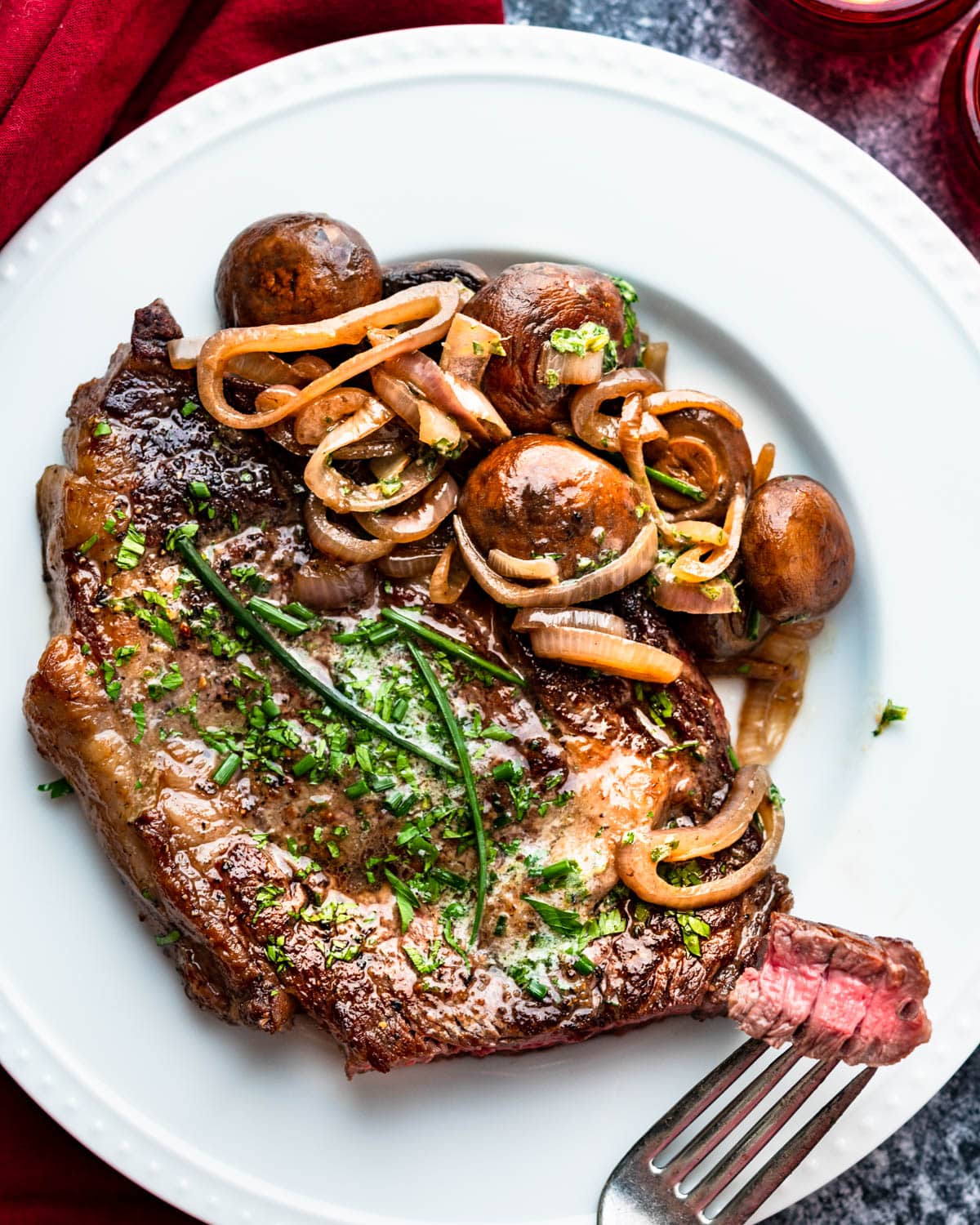 A pan-seared ribeye with mushrooms and onions.