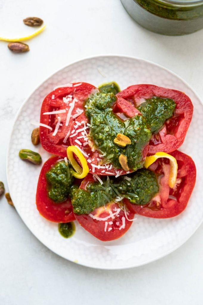 a plate of tomatoes dressed with pistachio pesto.