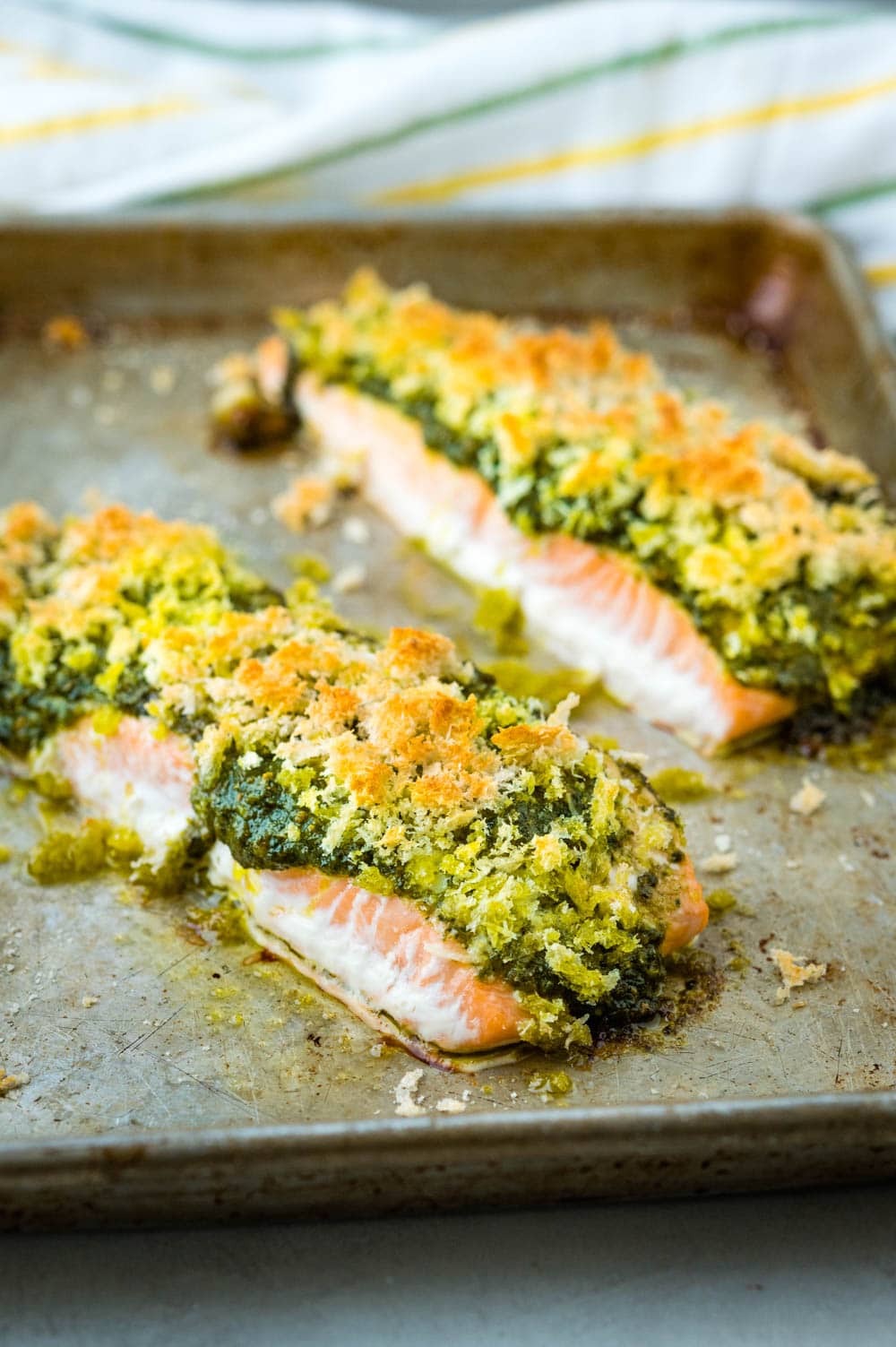 The golden crust and pesto sauce on the baked salmon fillets.