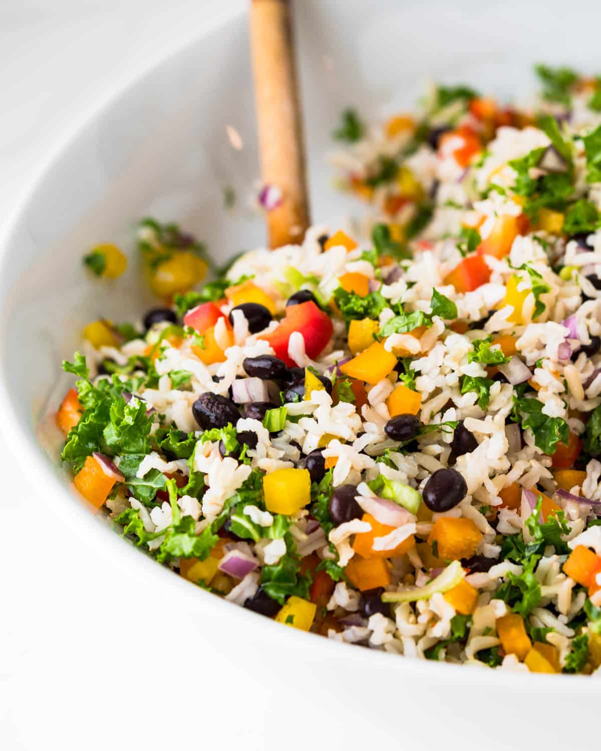 black bean and rice salad in a white bowl with a wooden spoon.