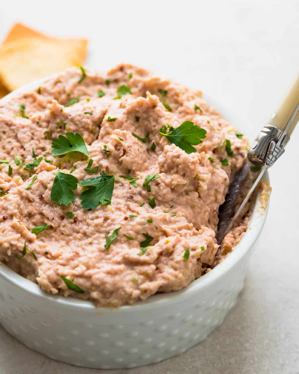 a crock of homemade deviled ham garnished with parsley.