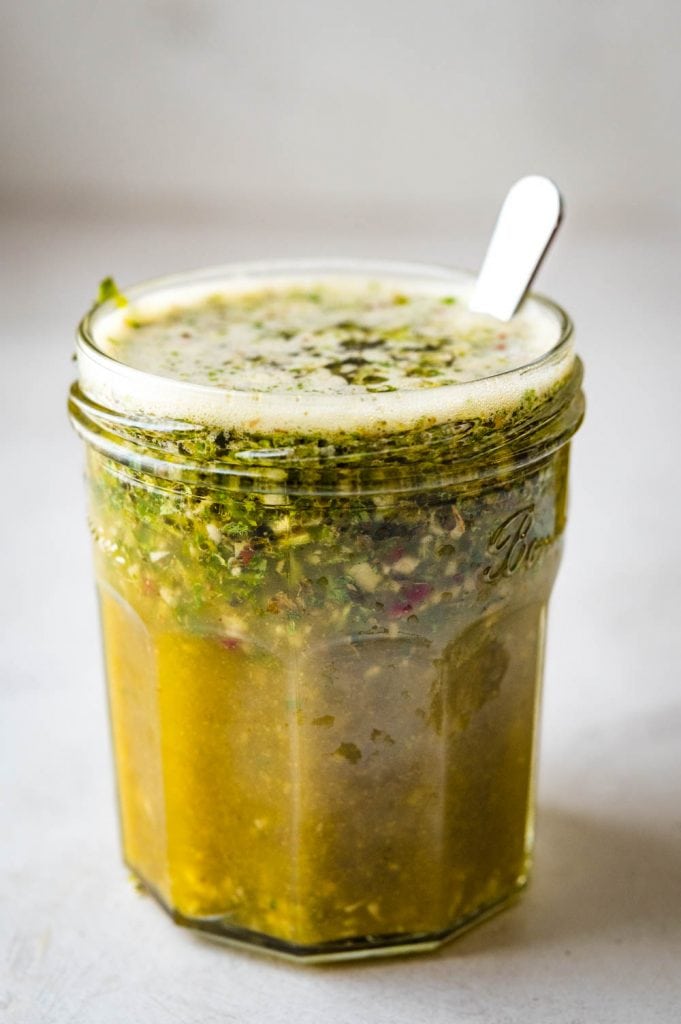 a jar of mojo marinade with herbs, garlic and spices.