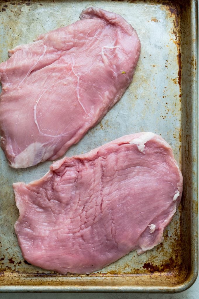 veal flank steaks on a rimmed baking sheet. 