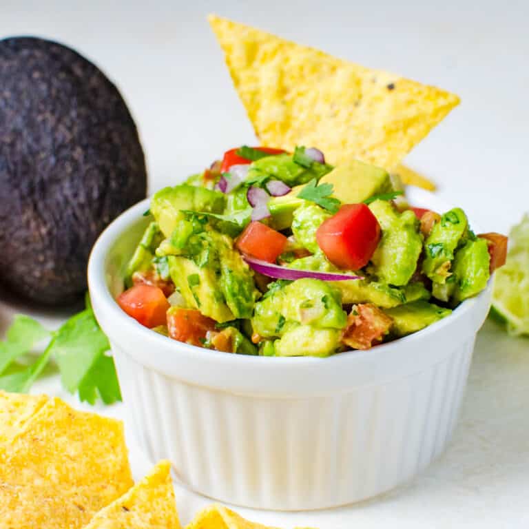 A dish of chunky guacamole with tortilla chips.