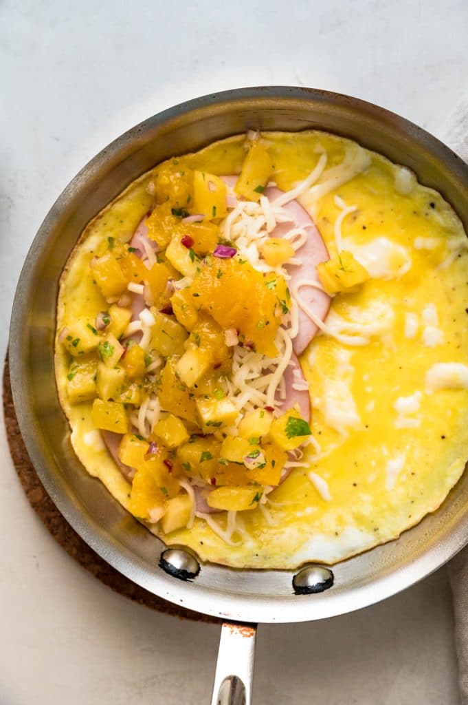 Topping the Hawaiian omelette with pineapple mango salsa for a healthy breakfast.