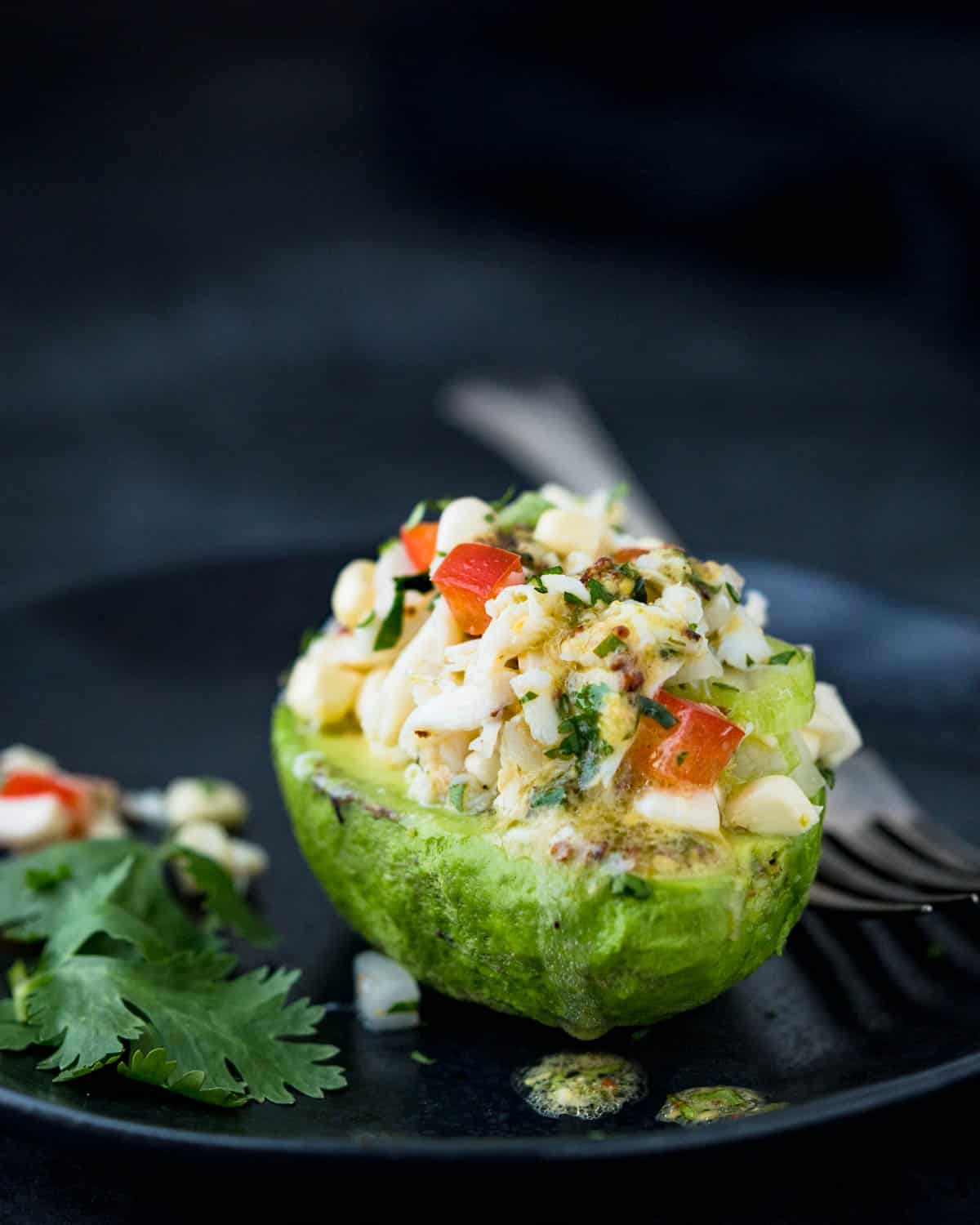 Half of an avocado filled with corn and crab salad.