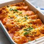 A baked beef enchilada casserole garnished with chopped cilantro.