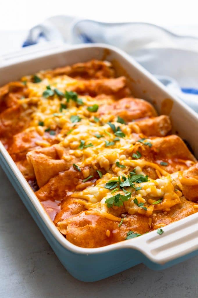 A baked beef enchilada casserole garnished with chopped cilantro.
