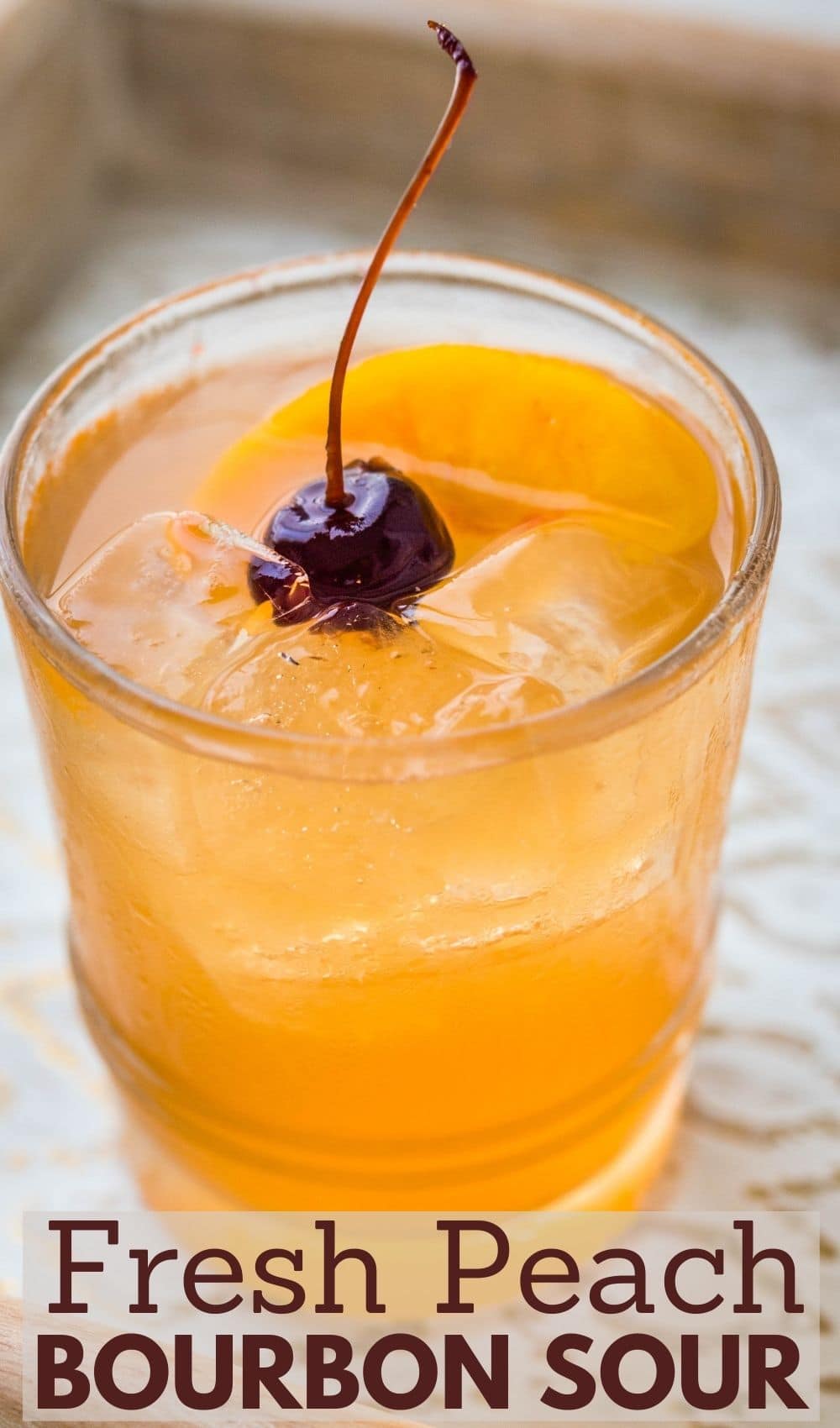 a peach whiskey sour with a cherry and peach garnish.