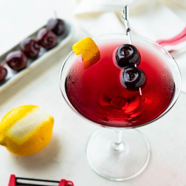 cherry martini with lemon garnish and skewered Drunken Cherries