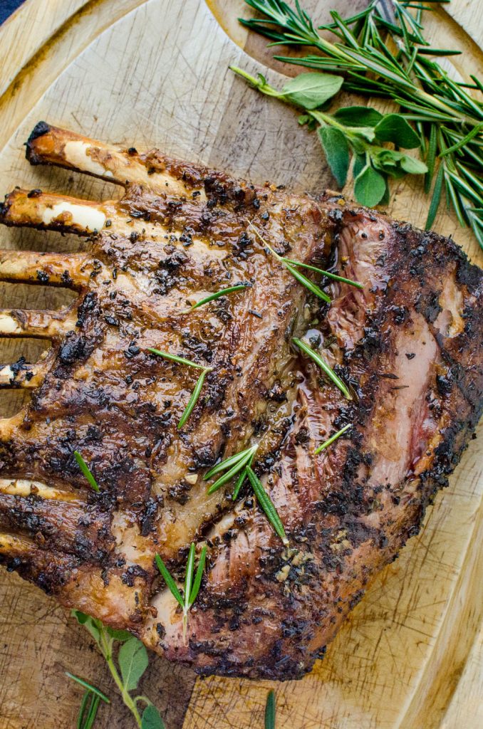 garlic and rosemary crusted grilled lamb resting on a cutting board.