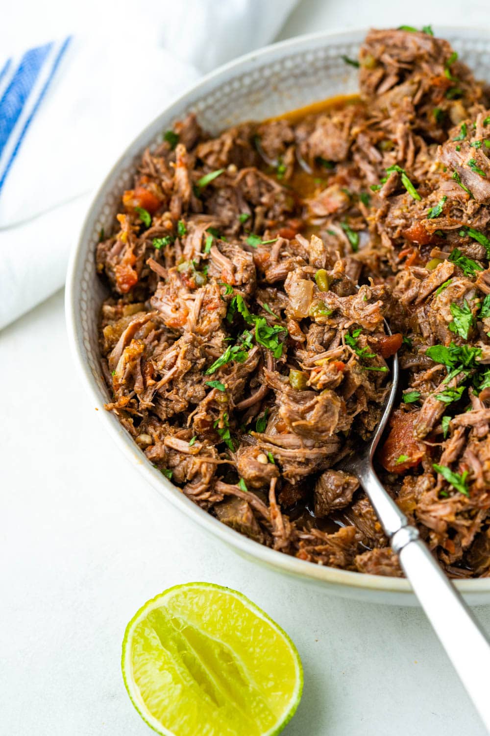 Mexican pulled beef in a bowl with a slice of lime.