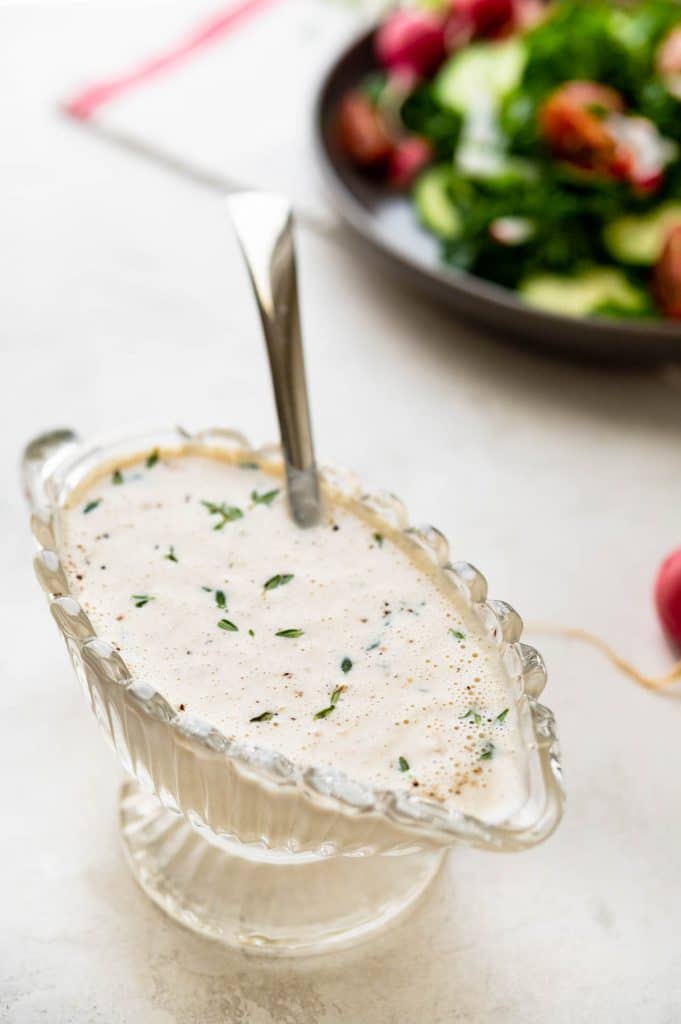 A serving dish of garlic dressing with a spoon.
