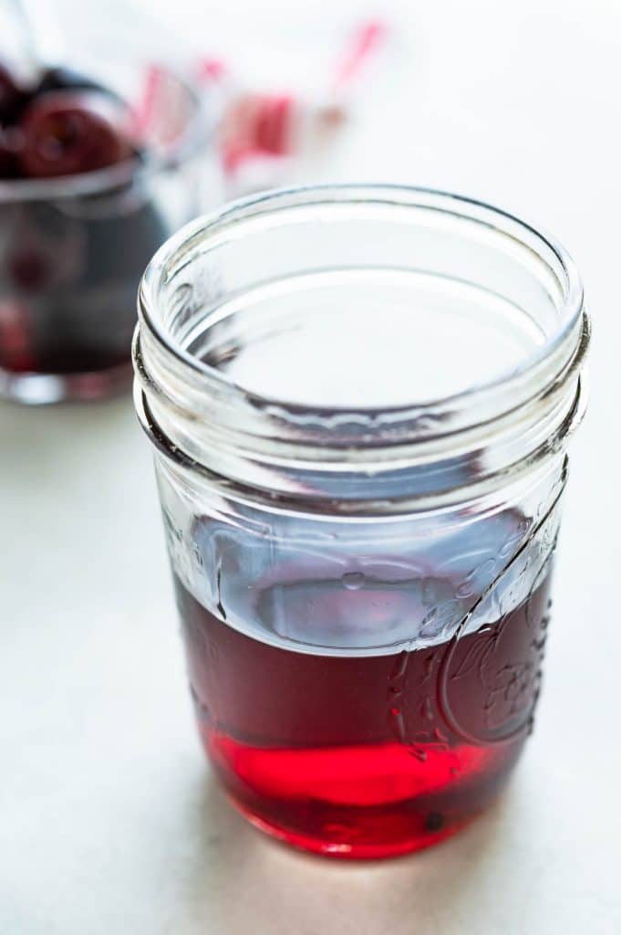 cherry infused vodka in a ball glass canning jar.