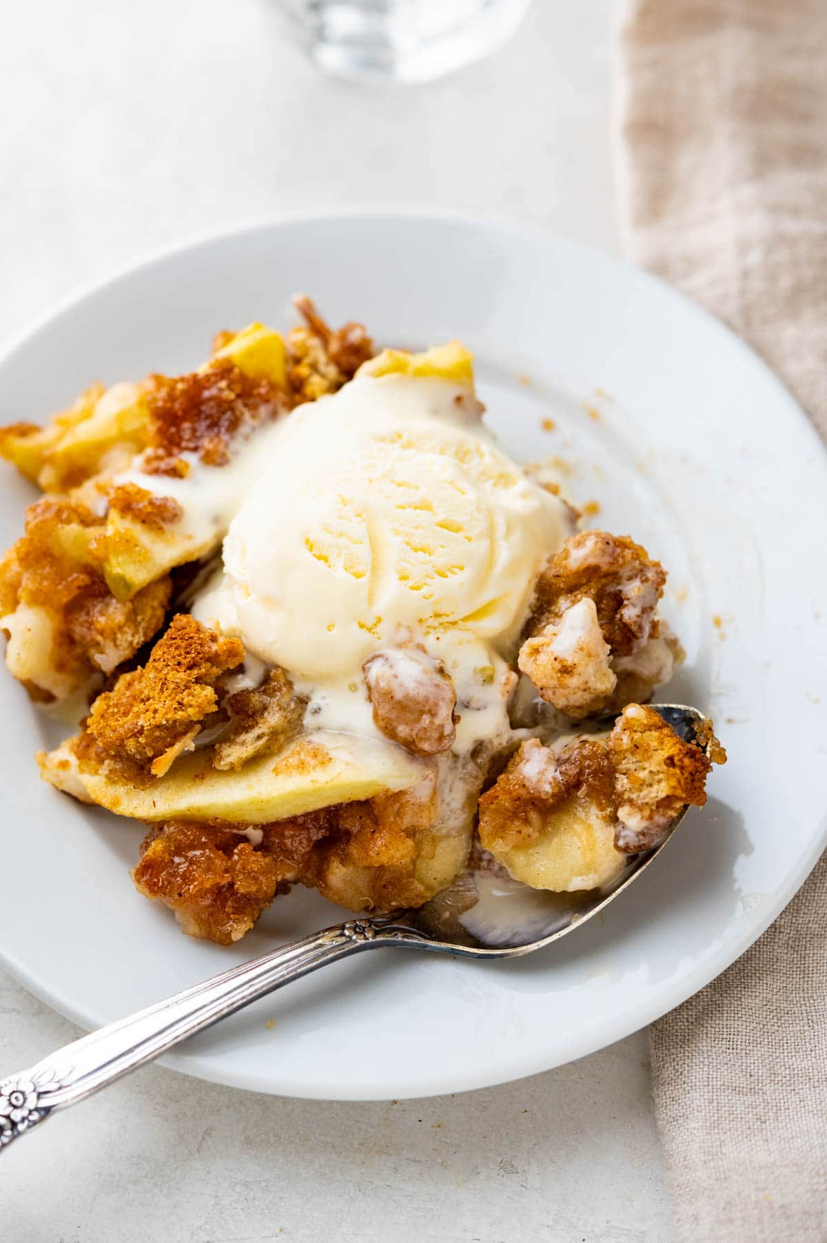 a serving of apple brown betty with a scoop of ice cream.