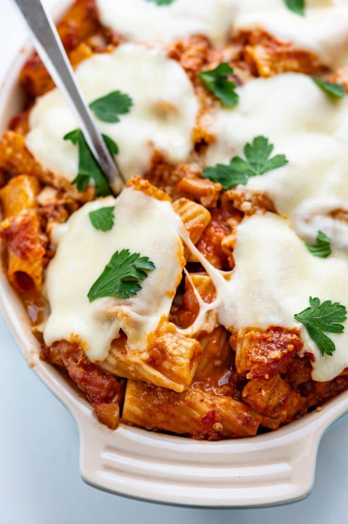 Cheesy baked chicken rigatoni hot from the oven with parsley garnish.