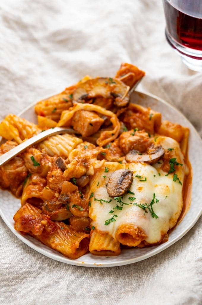 A serving of spicy chicken rigatoni with a glass of wine.