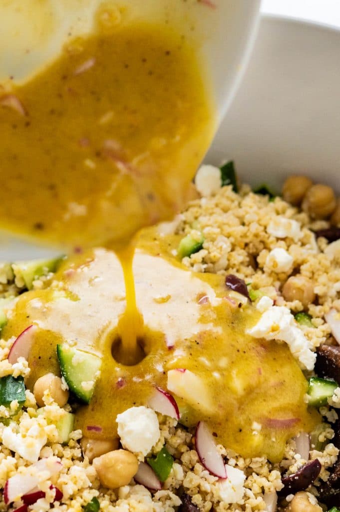 pouring vinaigrette over the millet salad recipe.