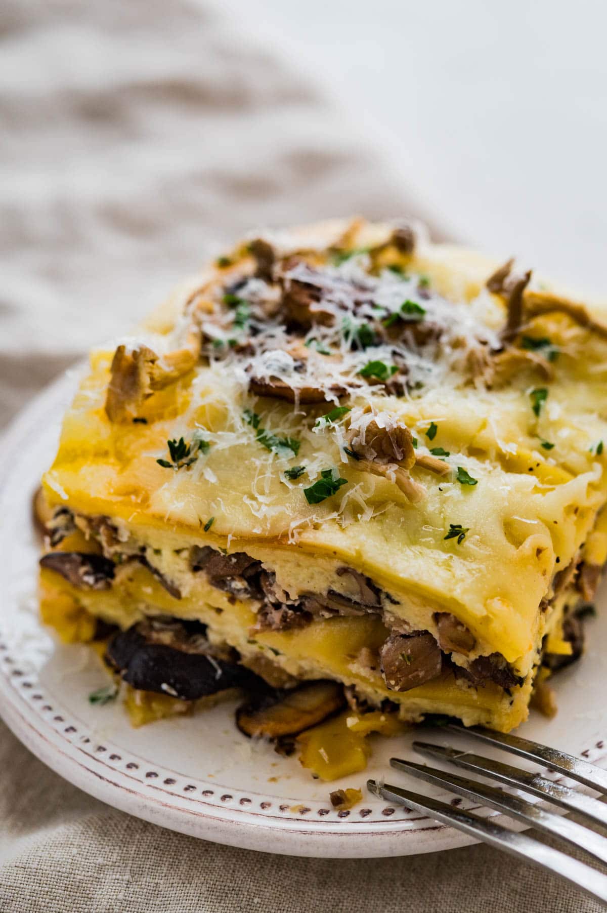 a slice of mushroom lasagna with a fork on a plate.