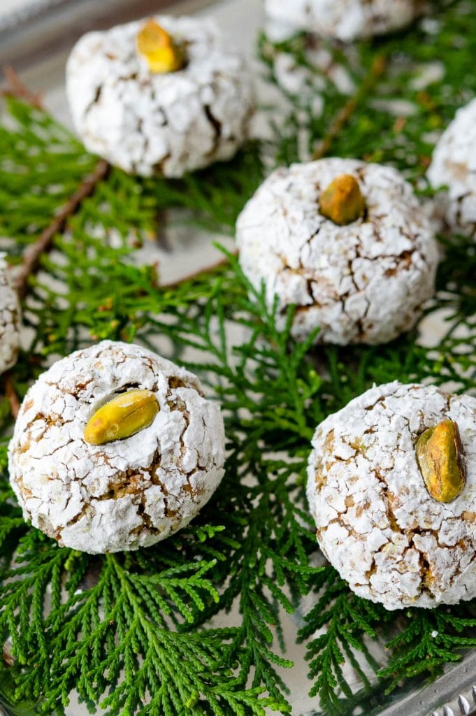 pistachio cookies on a tray with evergreen foliage.