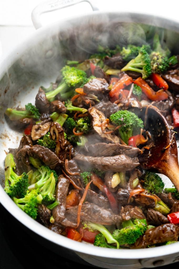 Adding the stir fry beef back to the skillet with the vegetables and broccoli.