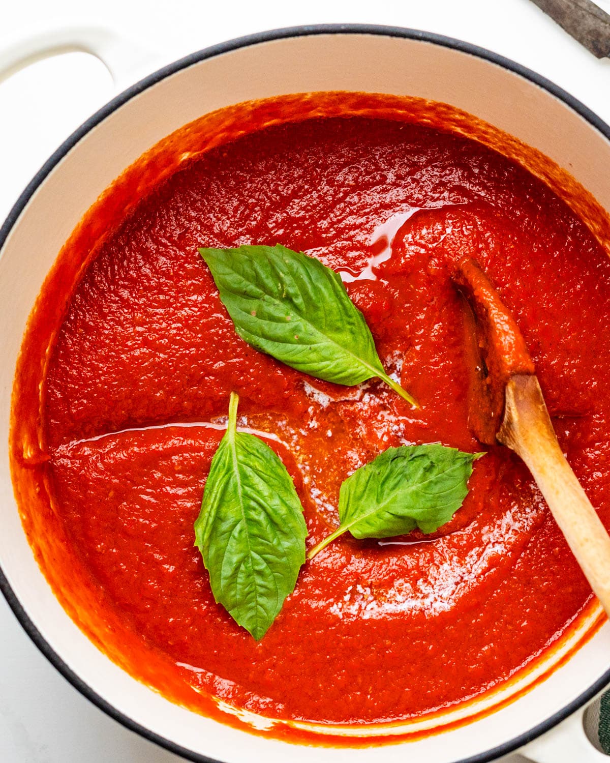 Homemade Pomodoro sauce with fresh basil leaves in a Dutch oven.