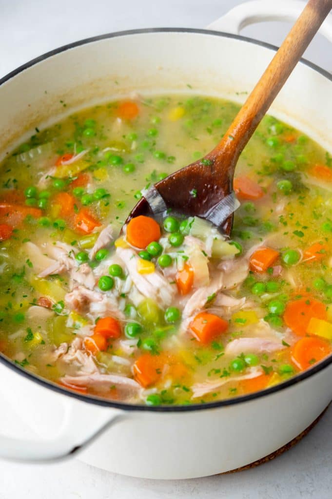a pot of turkey rice soup with a wooden spoon stirring.