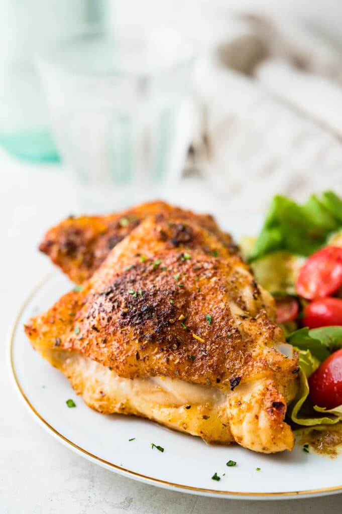 A serving of zesty baked chicken thighs with green salad.