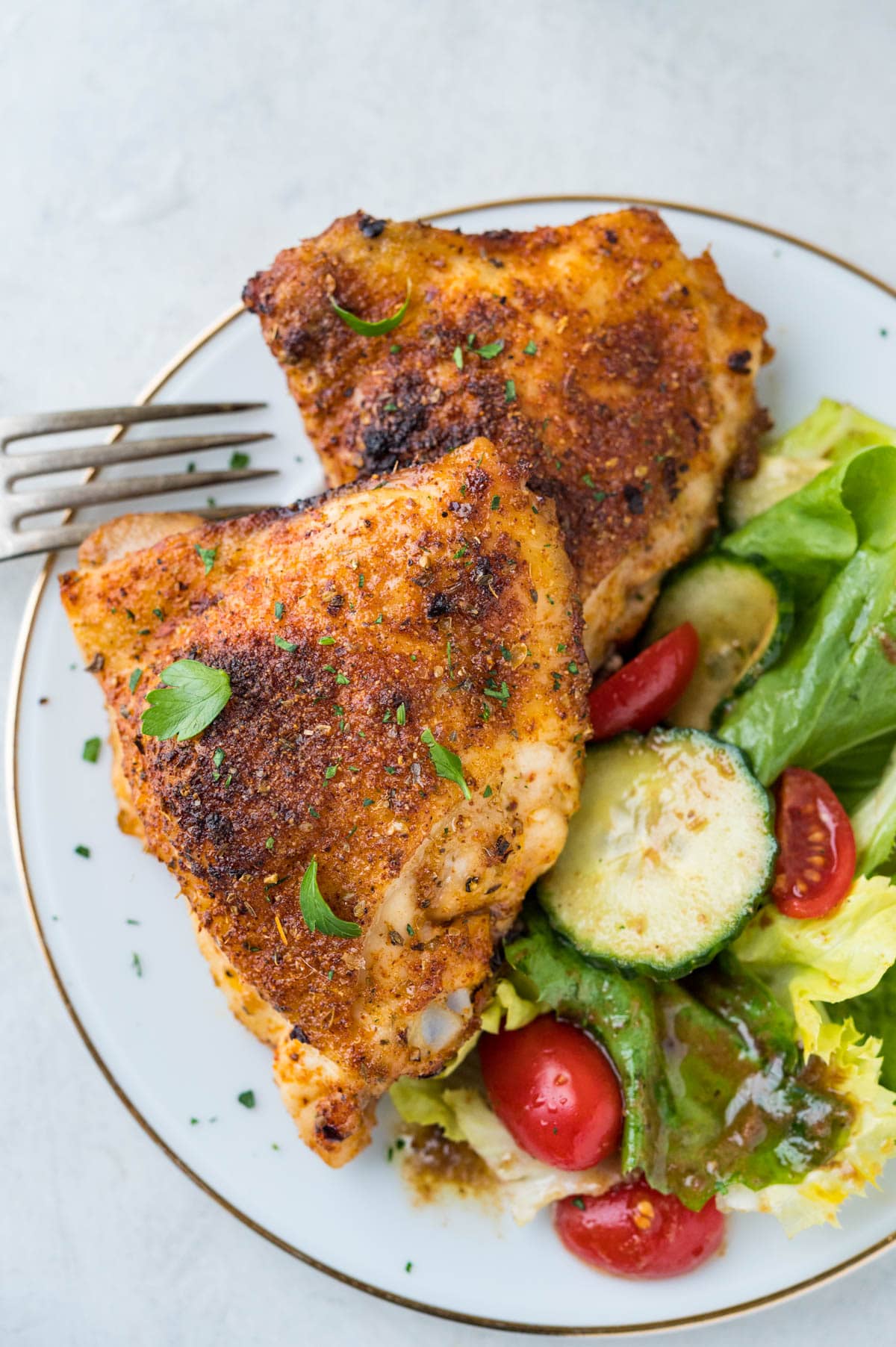 easy baked chicken thighs served with a green salad.
