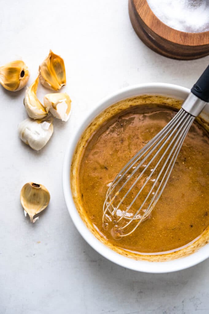 whisking the black garlic vinaigrette until thick and creamy.