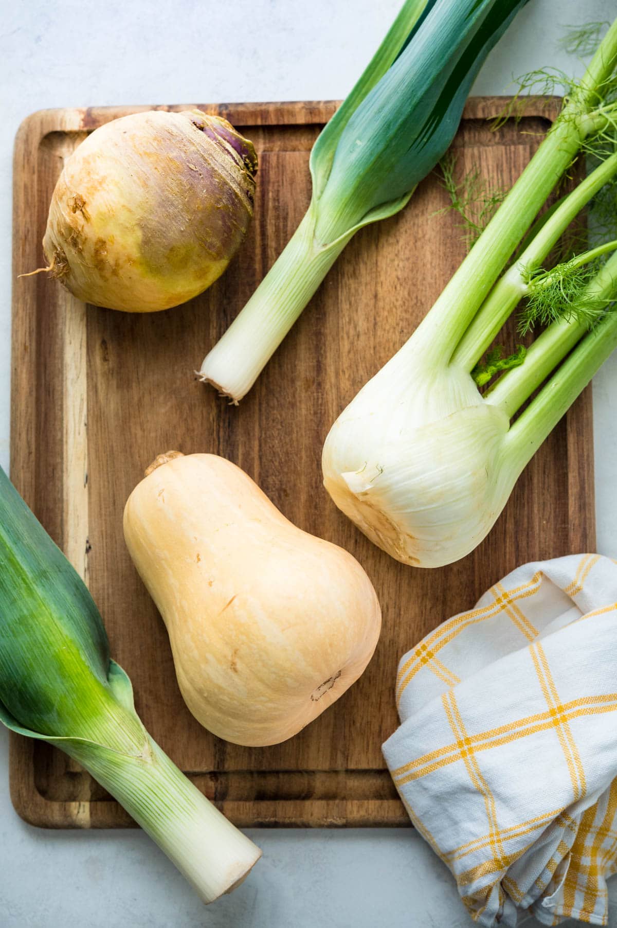 rutabaga, butternut squash, leeks and fennel on a cutting board.