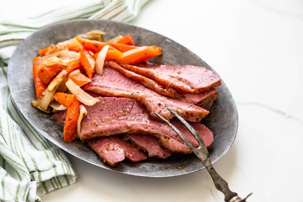 Using a serving fork to pick up a slice of corned beef. 
