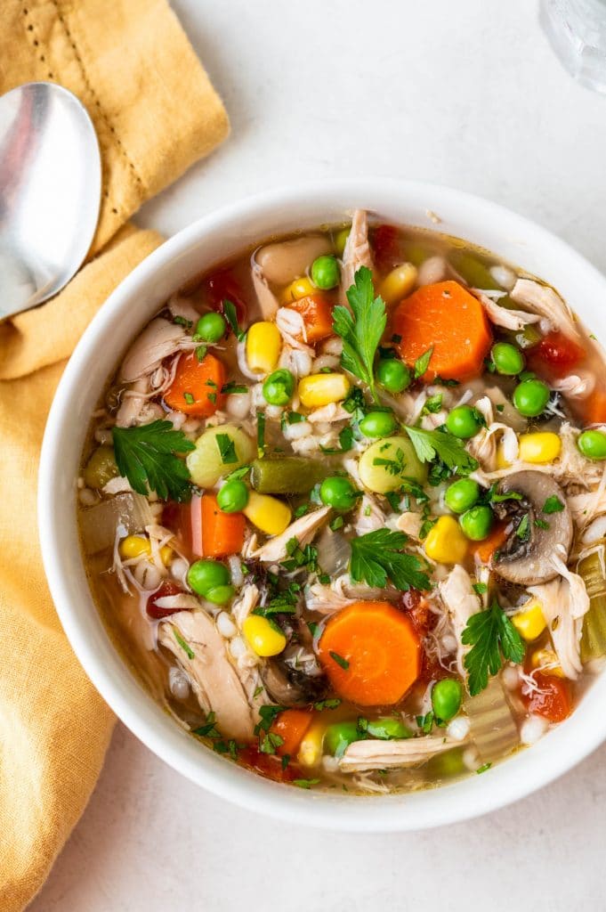 a bowl of chicken barley soup with fresh vegetables. 