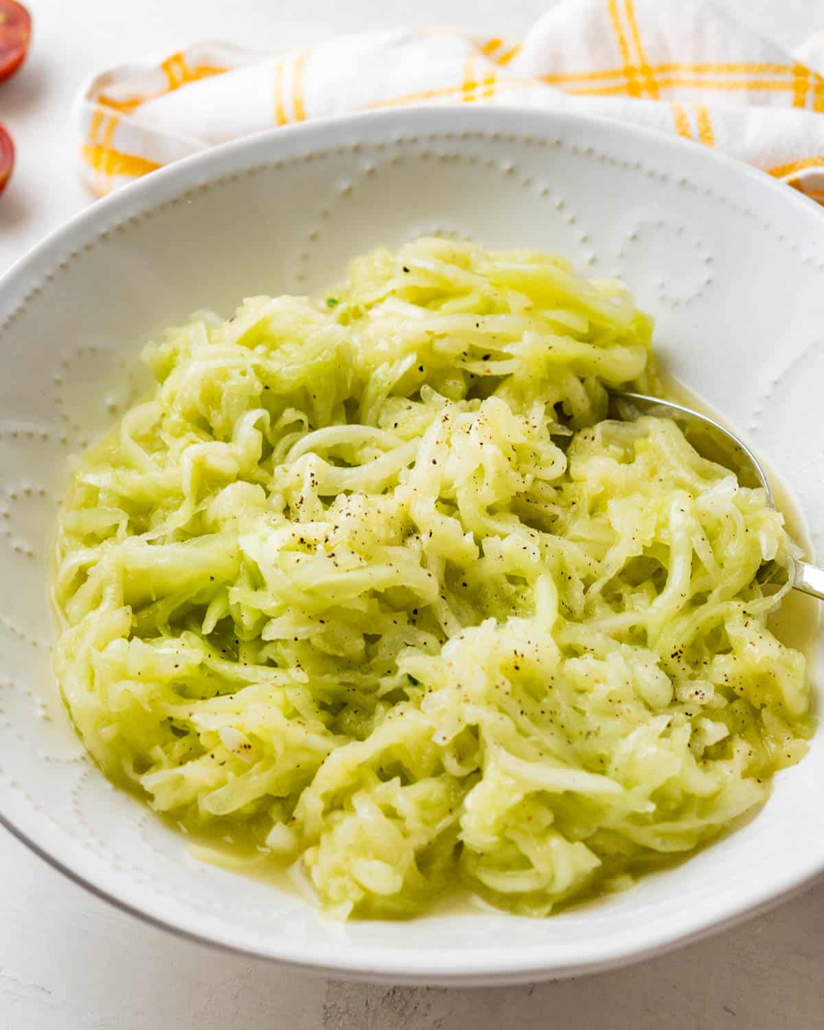 A bowl of the grated cucumber salad with a serving spoon.