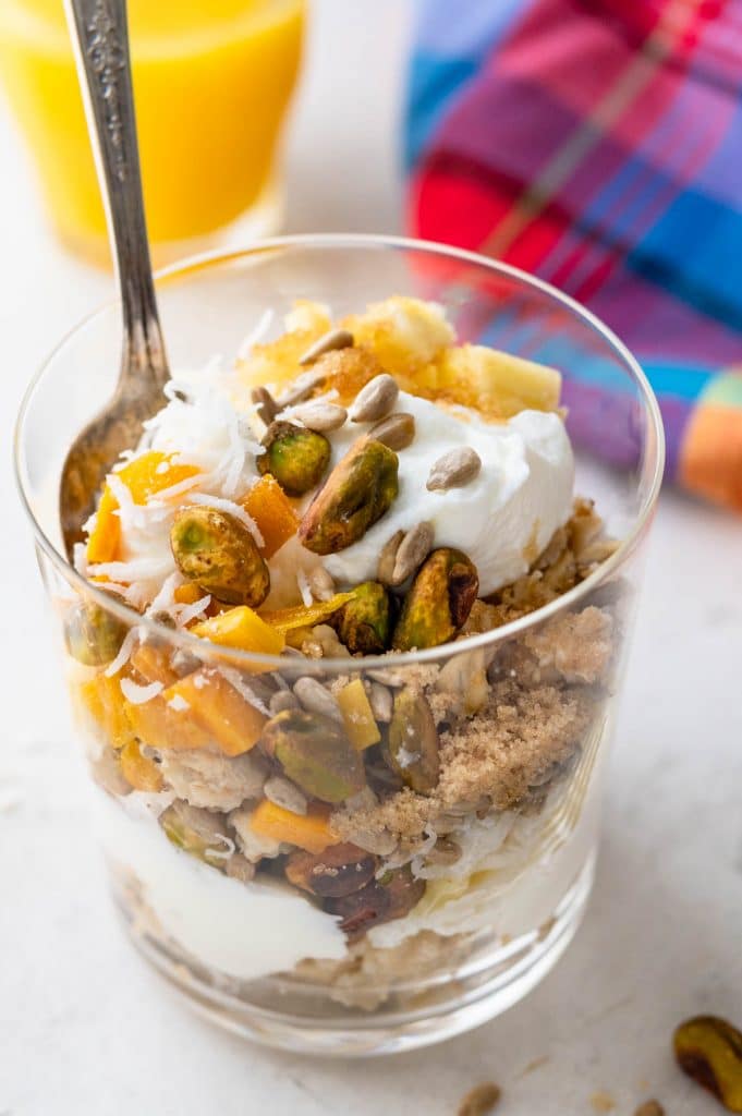 a photo of tropical muesli with mango, pineapple, coconut, brown sugar, yogurt and pistachios.