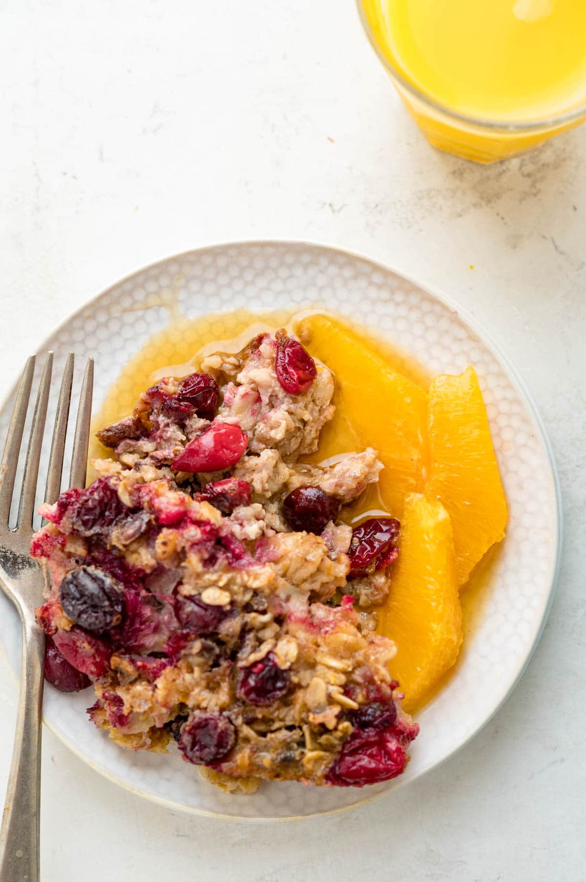 an overhead photo of the cranberry baked oatmeal with sliced oranges on a plate.