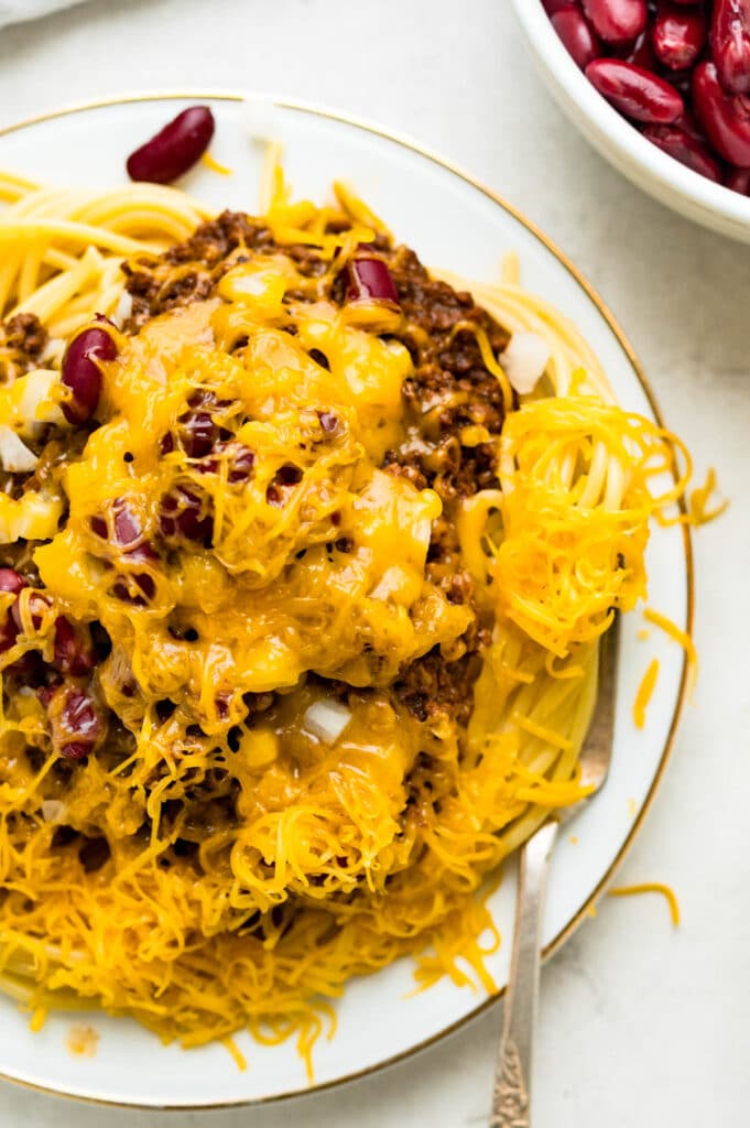 a serving of chili spaghetti with cheese, beans and onions.