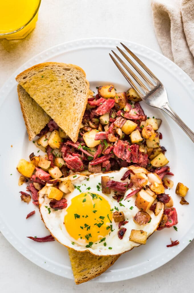corned beef hash and eggs on a plate with toast. 